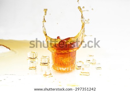 Whisky splash in a transparent glass and ice slices on a white background, dynamics of a liquid