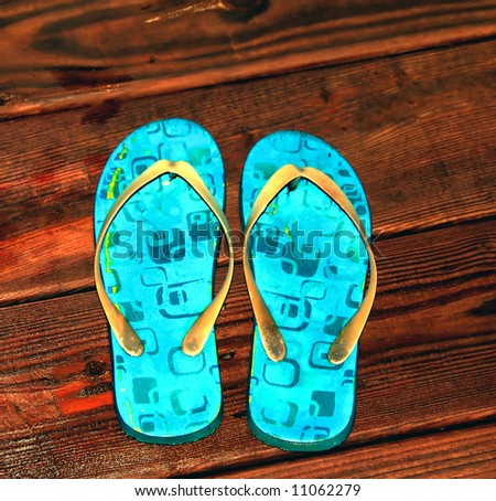 A pair of sandals on a wet wooden deck concept of tropical vacation
