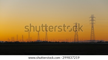 Silhouette of electrical power transmission pylons under sunset golden sky. The photo was taken at Baylands Nature Preserve in Palo Alto, California, by the south end of the San Francisco Bay.