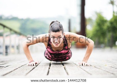 Young Woman Exercising Push-Ups on Wooden Floor.