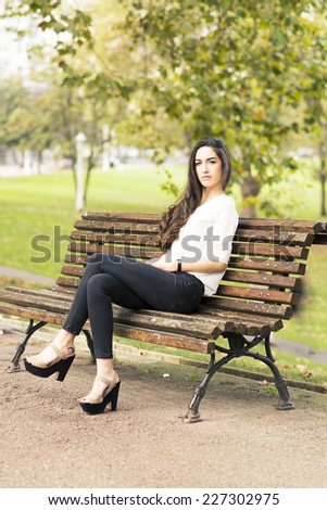Elegant beautiful woman sitting on bench in the park.