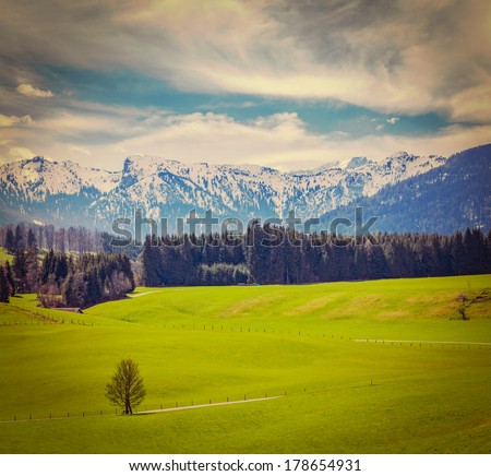 Vintage retro hipster style travel image of German idyllic pastoral countryside in spring with Alps in background. Bavaria, Germany