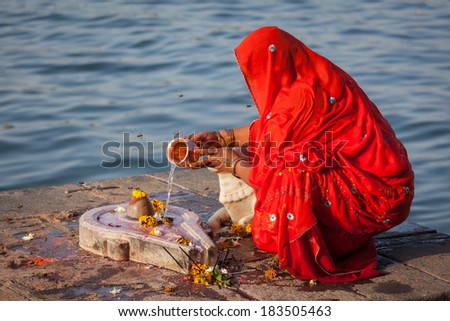 Indian woman performs morning pooja on sacred river Narmada ghats in Maheshwar, Madhya Pradesh, India. To Hindus Narmada is one of 5 holy rivers of India