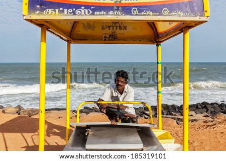 PONDICHERRY, INDIA - FEBRUARY 2, 2013: Unidentified Indian street ice cream vendor with cart on beach