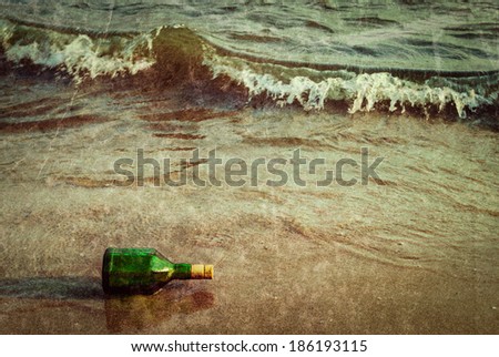 Vintage retro hipster style travel image of message bottle on beach sand in waves with grunge texture overlaid
