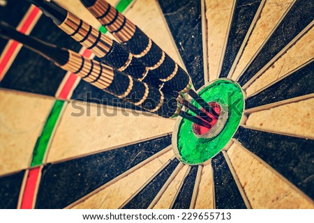 Vintage retro effect filtered hipster style image of  - Success hitting target aim goal achievement concept background - three darts in bull\'s eye close up