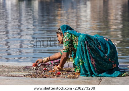 UDAIPUR, INDIA - NOVEMBER 24, 2012: Indian woman in Rajasthani traditional clothing selling jewellery on ghat of Lake Pichola, Udaipur, Rajasthan, India