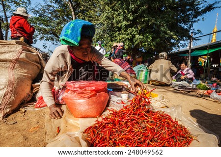INLE LAKE, MYANMAR - JANUARY 7, 2014: Woman selling hot red chilli pepper in rural market