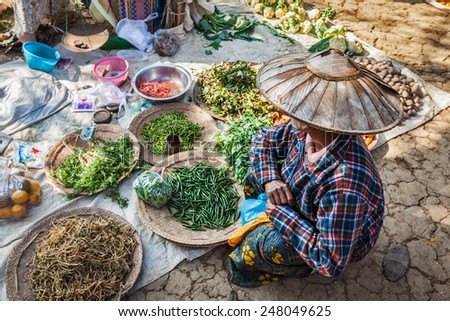 INLE LAKE, MYANMAR - JANUARY 7, 2014: Burmese woman selling vegetables in rural market