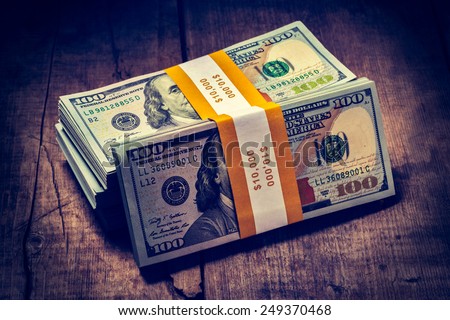 Creative business finance making money concept - Vintage retro effect filtered hipster style image of  stacks of new 100 US dollars 2013 edition banknotes (bills) bundles isolated on wooden background