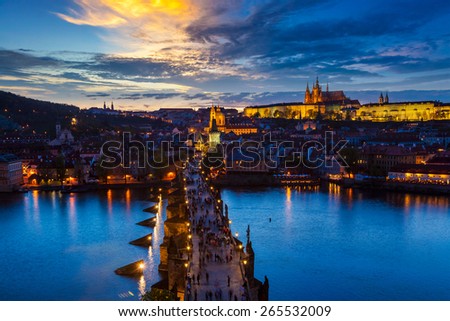Aerial view of illuminated Prague castle and Charles Bridge with tourist crowd over Vltava river in Prague, Czech Republic. Prague, Czech Republic in the evening