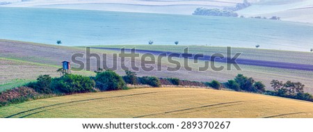 Rural Europe background - panorama of Moravian rolling landscape with hunting tower shack in early morning on sunrise. Moravia, Czech Republic
