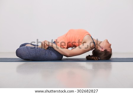 Beautiful sporty fit yogini woman practices yoga asana Matsyasana - fish pose in studio