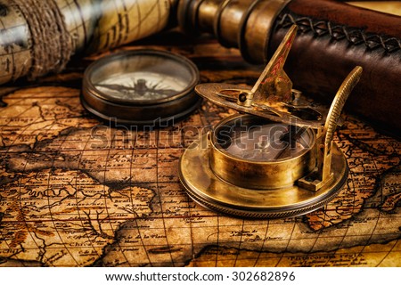 Travel geography navigation concept background - old vintage retro compass with sundial and spyglass on ancient world map with copyspace