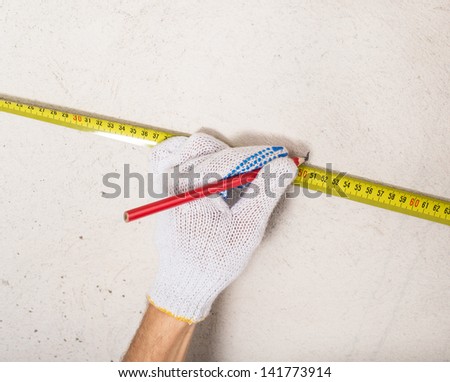 workers hand measuring plaster wall