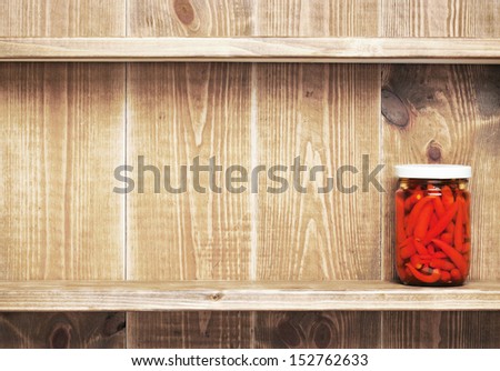 Preserved  autumn vegetable on shelf near a brown wooden wall