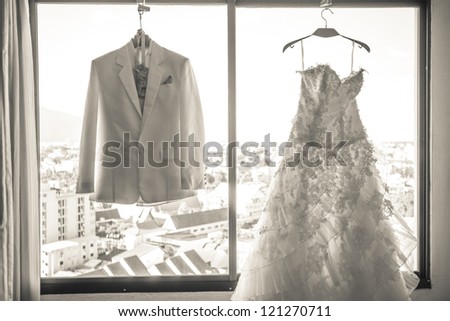 Wedding dress and suit hanging in a window.