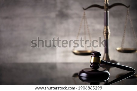 Law and justice concept. Mallet of the judge, hourglass, scales of justice. Gray stone background, reflections on the floor. Place for typography.