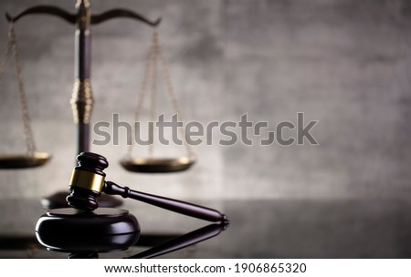 Law and justice concept. Mallet of the judge, hourglass, scales of justice. Gray stone background, reflections on the floor. Place for typography.