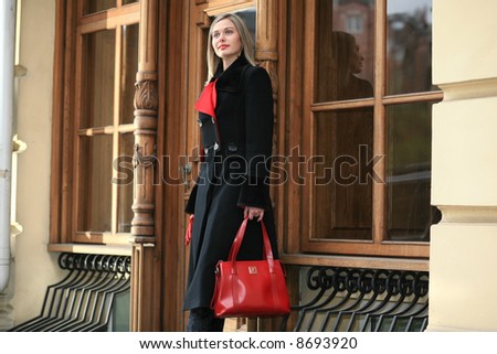 beautiful young woman in a black coat costs on a step