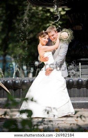 Groom and bride joy against backdrop fountain