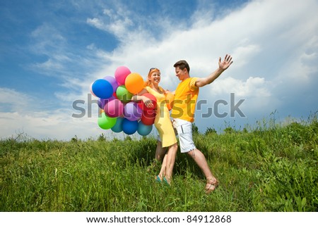 man and woman playing with balloons against a blue sky