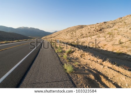Lonley aslphalt desert highway disappearing off into mountains.