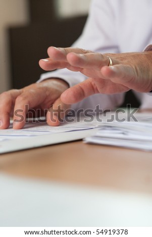 Businessman sitting on his table and gesticulating with his left hand