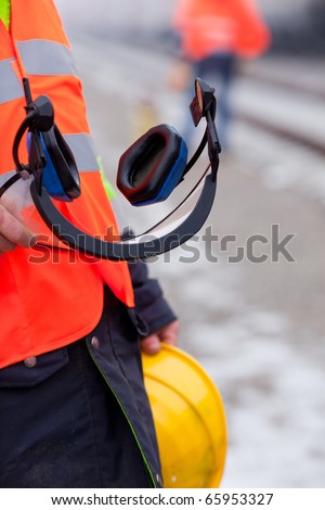 a worker shows his helmet and ear protectors