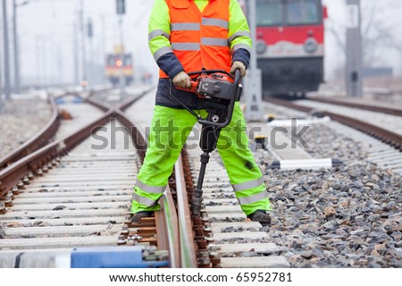 a railroad worker unscrews a screw on the rails