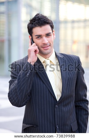 young european businessman holding his mobile phone against his ear while going through the streets