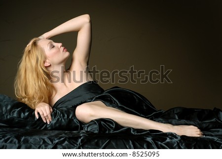 Beautiful woman on black satin sheets