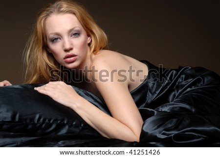 Beautiful woman relaxing on black satin sheets