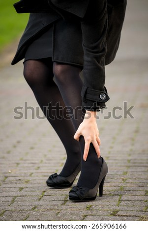 Painful cramps in the calf of an elegant woman dressed in black
