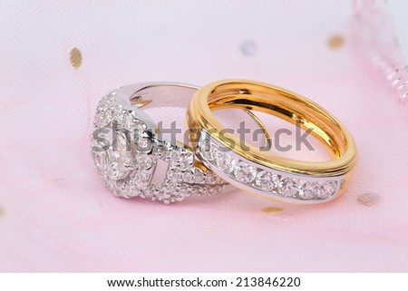 Golden diamond ring and contemporary diamond ring on pink background