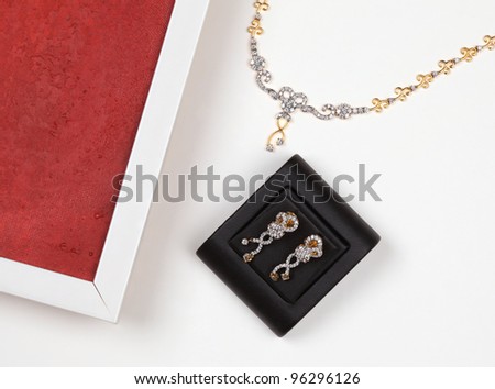 Beautiful diamond earring, golden necklace with diamond and part of flame isolated on white background.