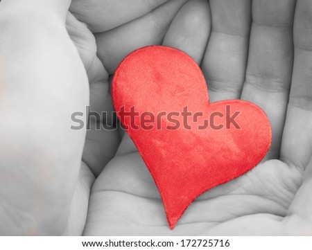 Red cloth heart in hands. Selective focus.