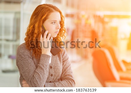 Redhead girl speaking by phone. Selective focus with shallow depth of field.