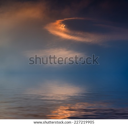 Dramatic sunset clouds reflected in water.
