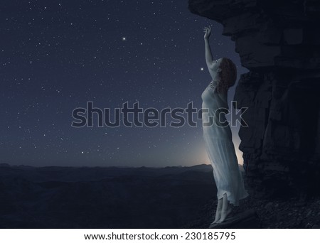 Young woman standing on cliff\'s edge of another planet and looks into the distance.