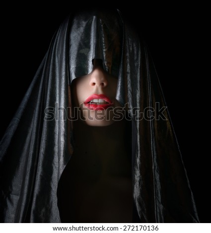 Portrait of beautiful woman in cape on dark background.