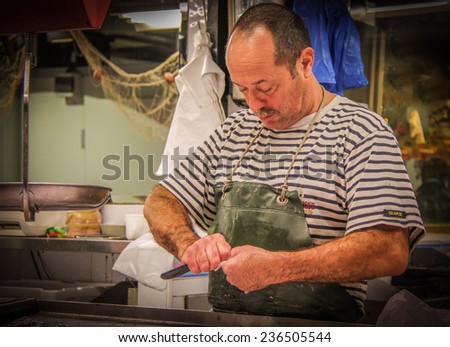 SETE, FRANCE - NOVEMBER 2: Fish vendor cleaning fish at the market on November 2, 2014 in Sete, France