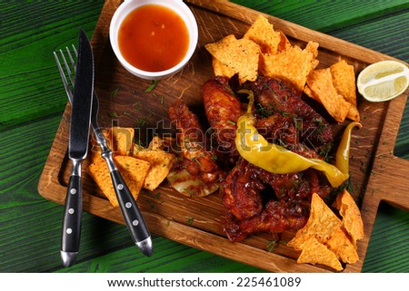 Grilled chicken with chips and jalapeno pepper on wood board with cultery top view