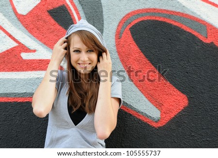 Young and beautiful girl posing against wall with graffiti