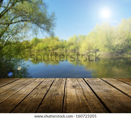 Empty wooden deck table with spring lake in background. Ready for product display montage.