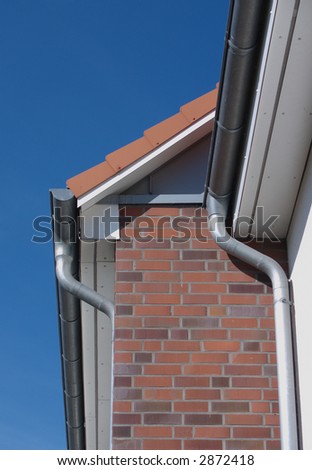 part of a house with roof, gutter and bricks