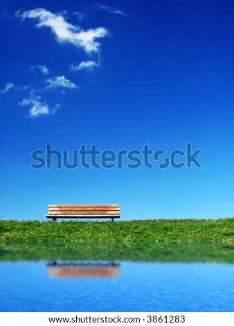 lonesome bench on green grass under a deep blue sky with some white clouds