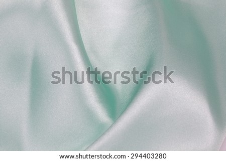Light green Silk cloth of abstract background or wavy folds or satiny silk texture satin velvet material or elegant wallpaper design curve.