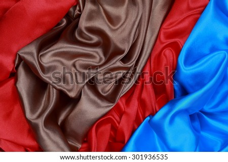 Blue and brown and red silk texture satin velvet material or elegant wallpaper design curve folds wavy background