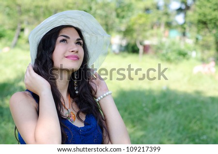beautiful young woman in hat enjoys summer in the park